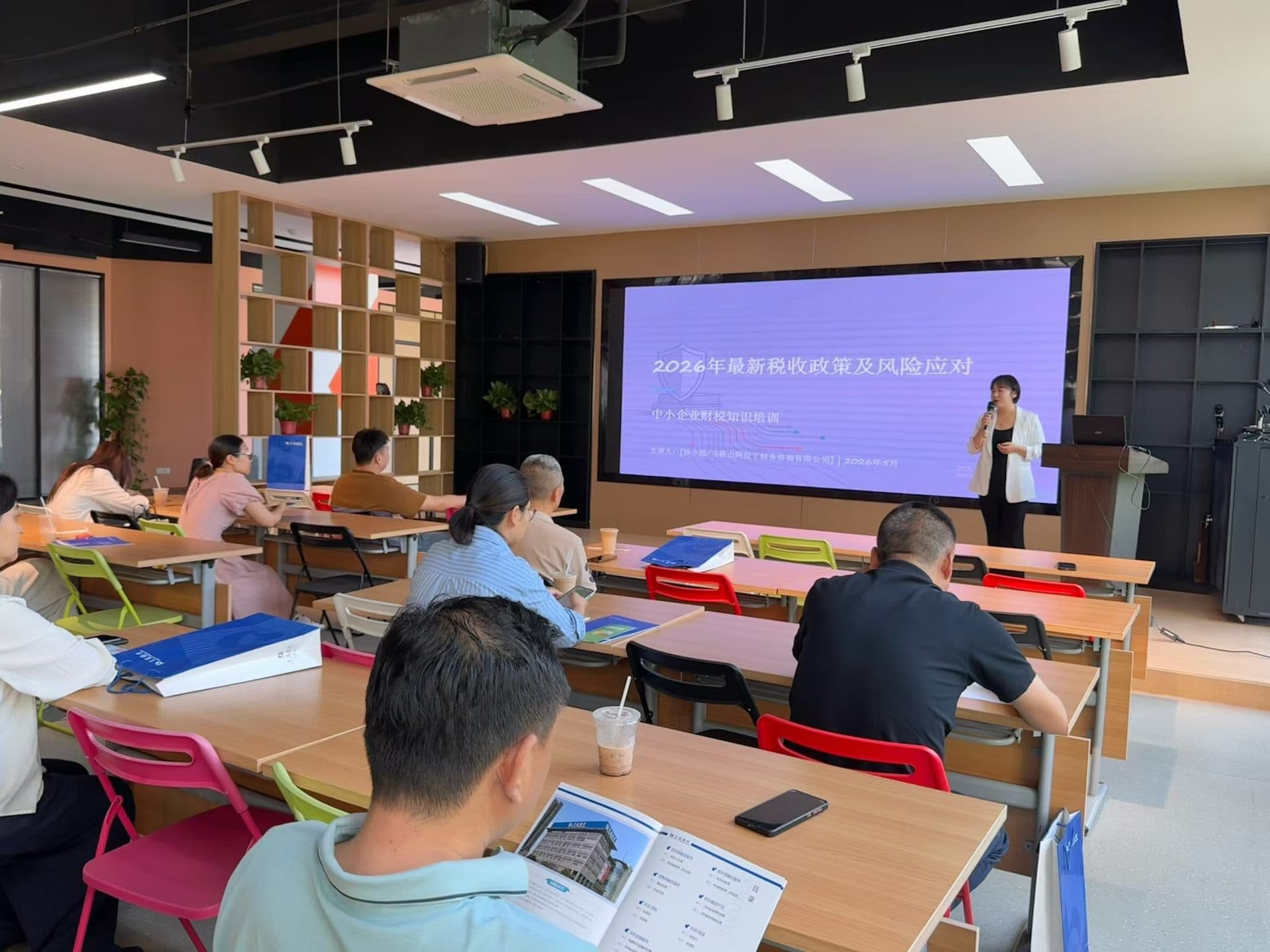 Professional tax policy training session with presenter, audience, and presentation screen